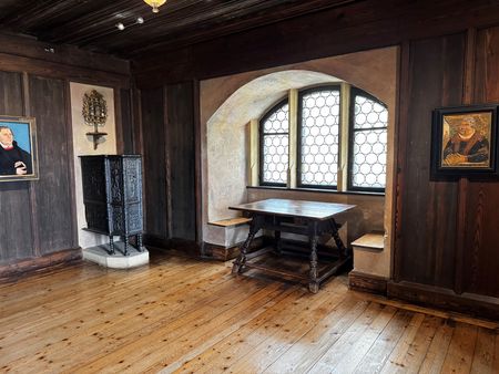 Das Lutherzimmer in den Kunstsammlungen der Veste Coburg mit einer Sitzbank und einem Tisch sowie einem Porträt von Martin Luther. 