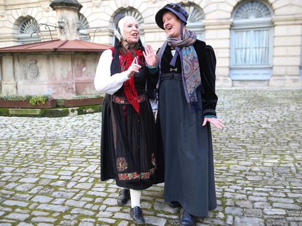 Die Coburger Marktfrau steht mit Fräulein Therese am Brunnen von Schloss Ehrenburg.