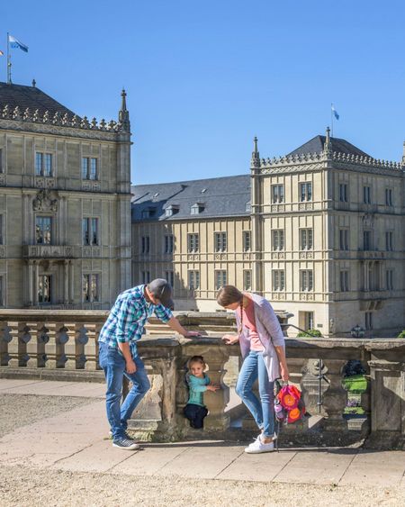Familie steht auf den Arkaden und dahinter ist Schloss Ehrenburg zu sehen.