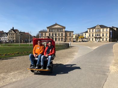 Eine Fahrradrikscha mit zwei Personen auf dem Schlossplatz in Coburg.